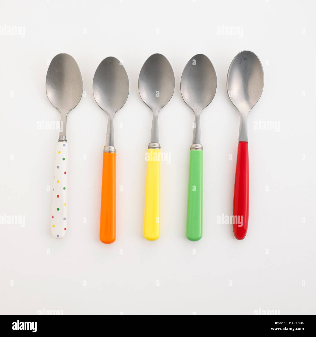 Fila di cucchiaini con maniglie colorate Foto Stock
