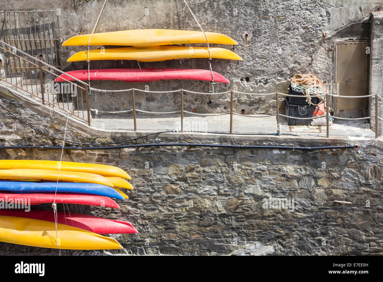 Il giallo e il rosso in plastica canoe, appesa sul muro di pietra, Riomaggiore  Cinque Terre Foto stock - Alamy