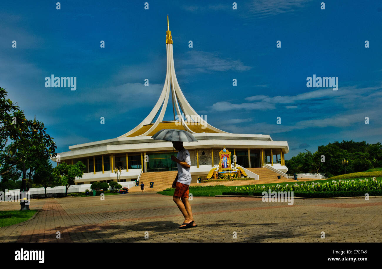 Uomo che cammina con il suo bianco ombrellone presso il King's Park Rama IX, Bangkok, Thailandia Foto Stock