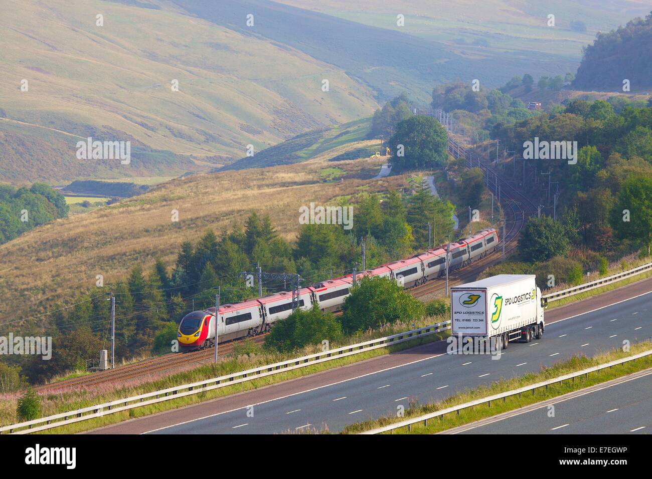 Classe 390 Pendolino Virgin treno passa l autostrada M6 nel fiume Lune Valley. Howgills, Cumbria, Linea principale della costa occidentale, UK. Foto Stock