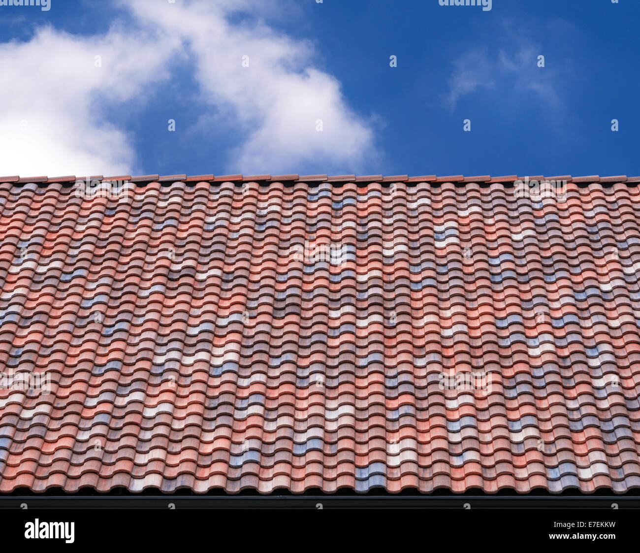Variopinto tetto tegola contro il cielo blu e nuvole bianche Foto Stock