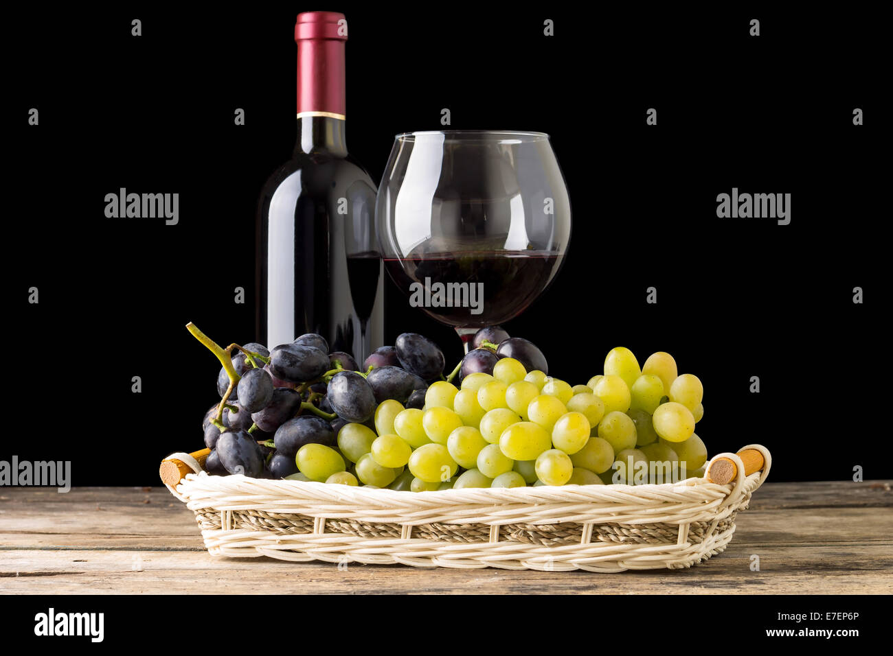 Cantina still-life. Diverse varietà di uve con wineglass e una bottiglia di vino bianco su sfondo nero Foto Stock