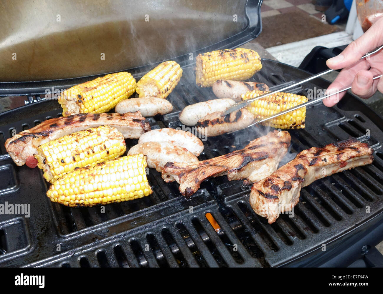 La cottura di alimenti in un gas-powered barbecue, Londra comprese salsicce di maiale da allegre Pig Foto Stock