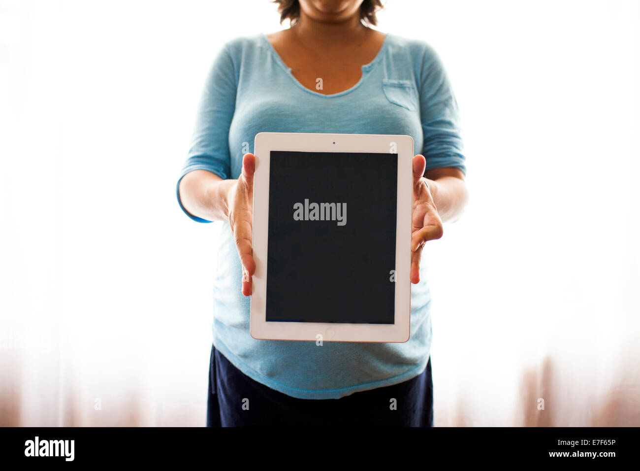 Incinta donna ispanica azienda computer tablet Foto Stock