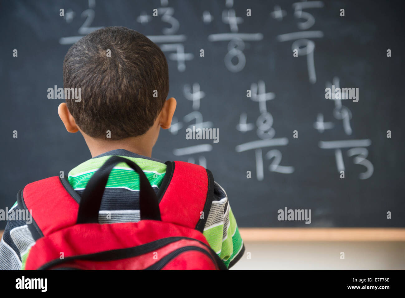 Razza mista boy facendo problemi matematici a bordo nella classe Foto Stock