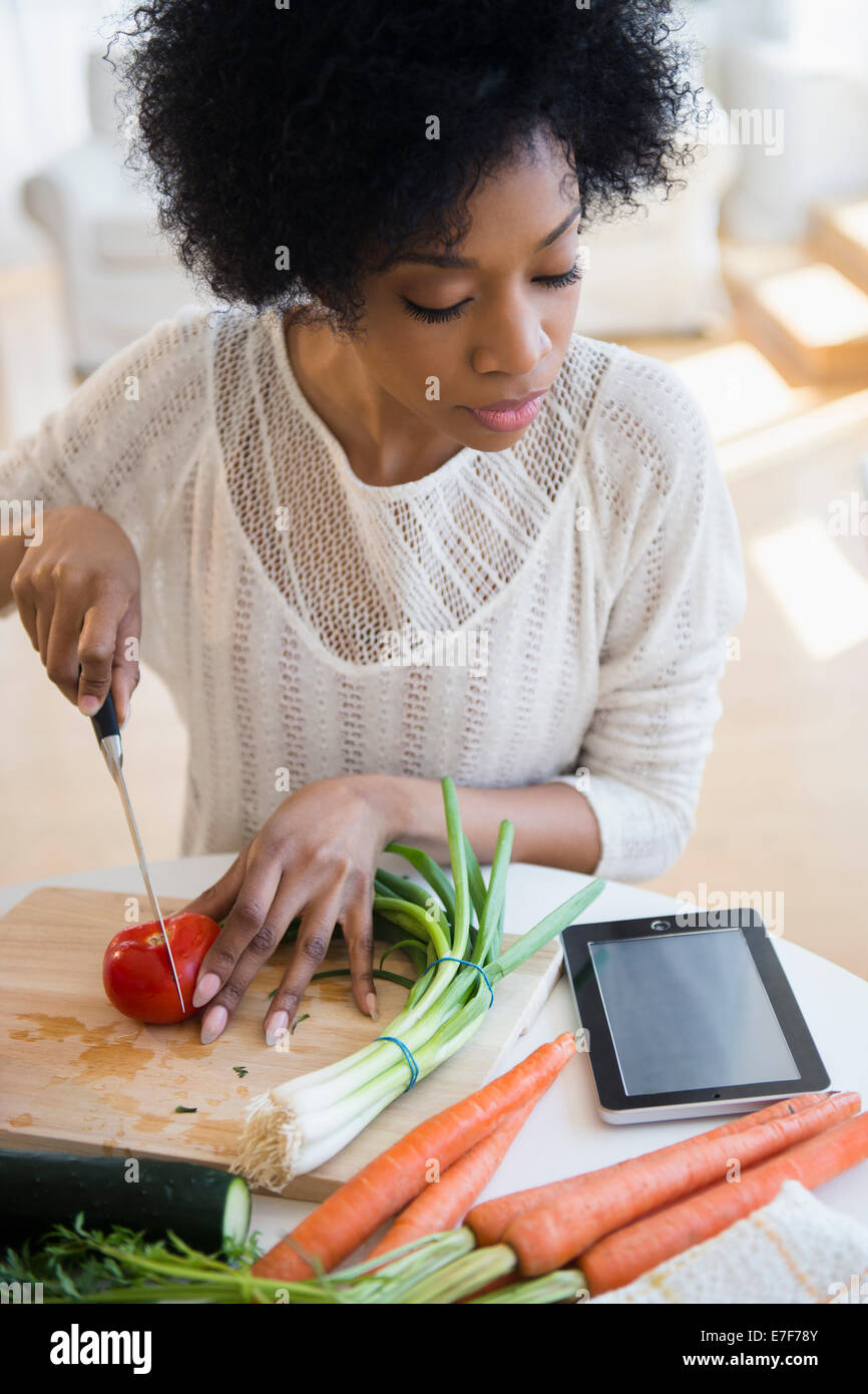 African American donna utilizzando computer tablet per cucinare Foto Stock