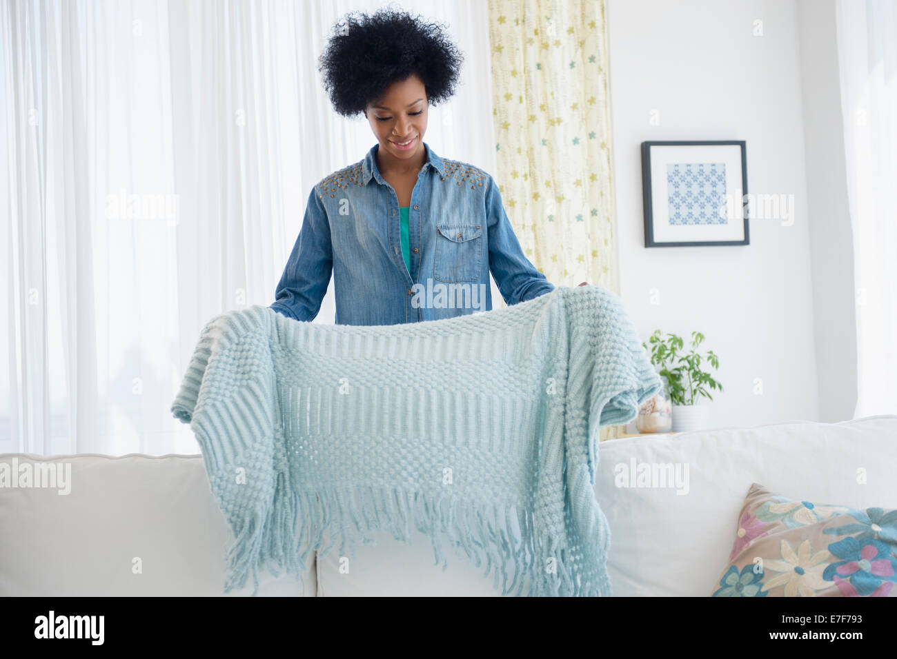 African American donna coperta di piegatura sul divano Foto Stock