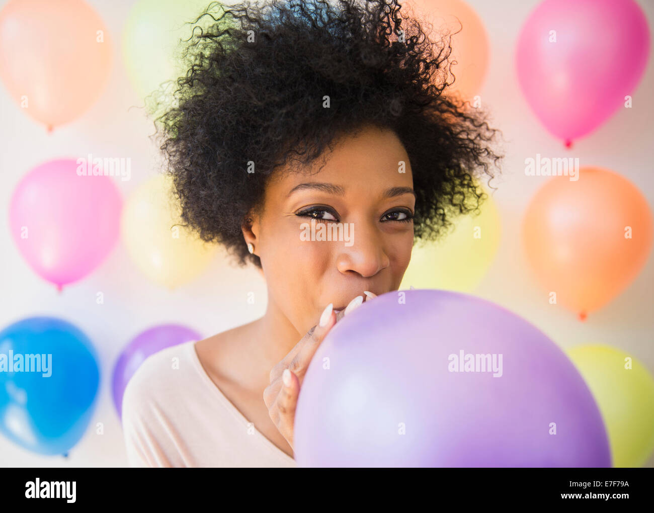 African American donna che soffia su palloncino per party Foto Stock