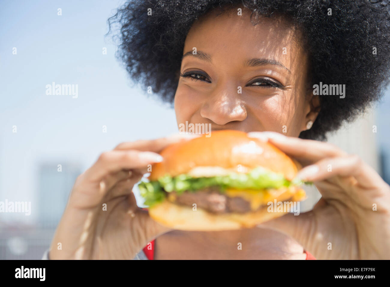 African American donna mangiare cheeseburger Foto Stock