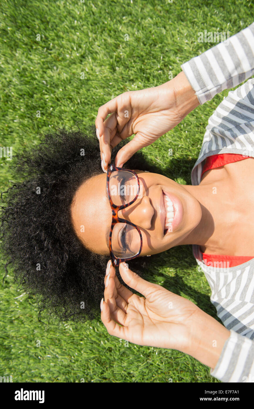 African American donna posa in erba indossando occhiali da vista Foto Stock