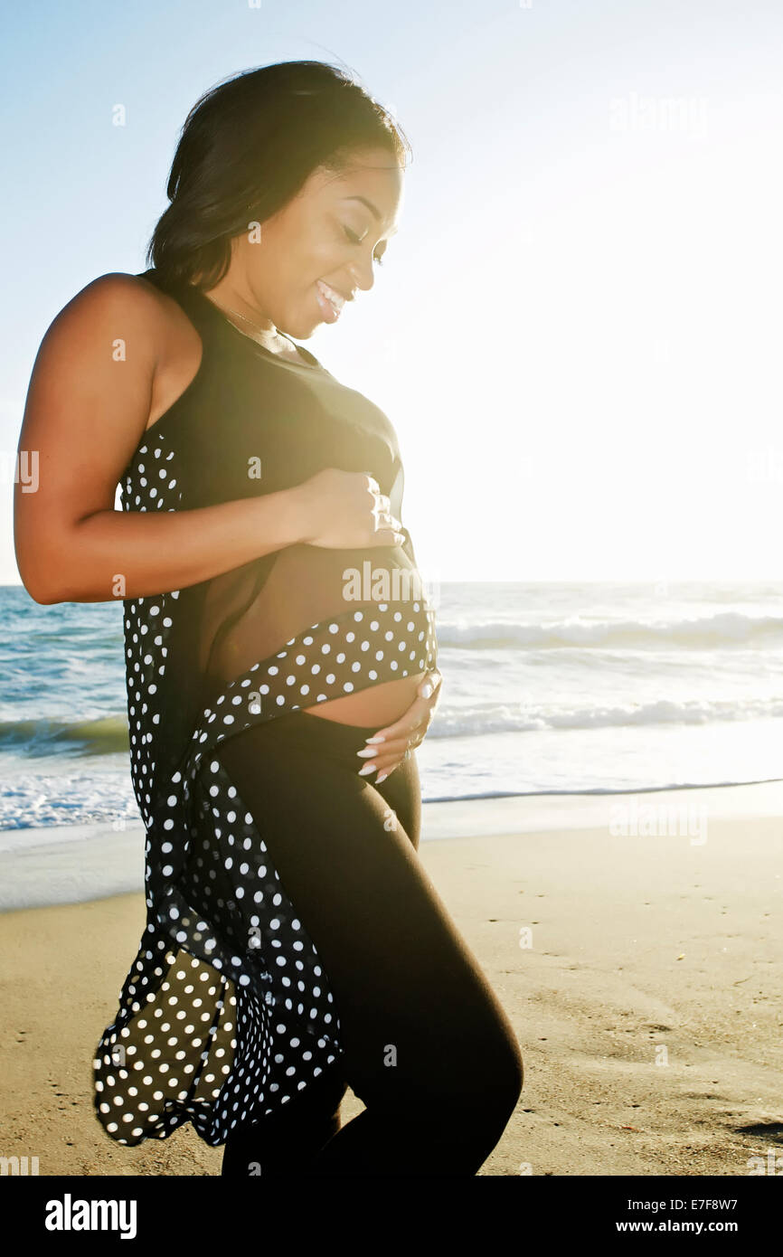 Donna incinta mentre tiene il suo ventre sulla spiaggia Foto Stock