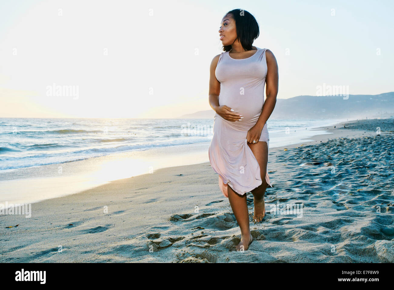 Donna incinta mentre tiene il suo ventre sulla spiaggia Foto Stock