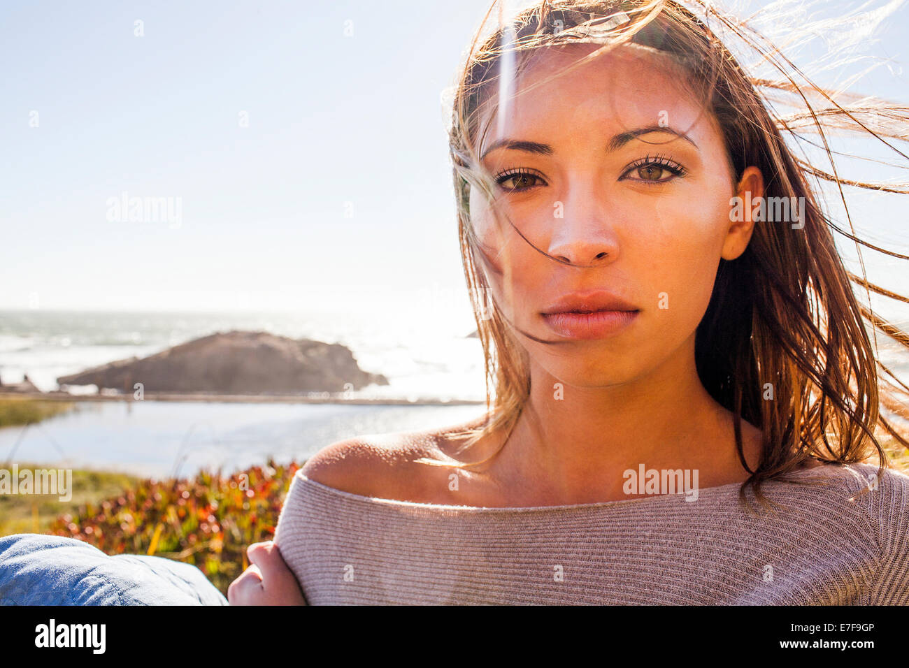 Razza mista donna capelli soffiando nel vento sulla collina costiera Foto Stock