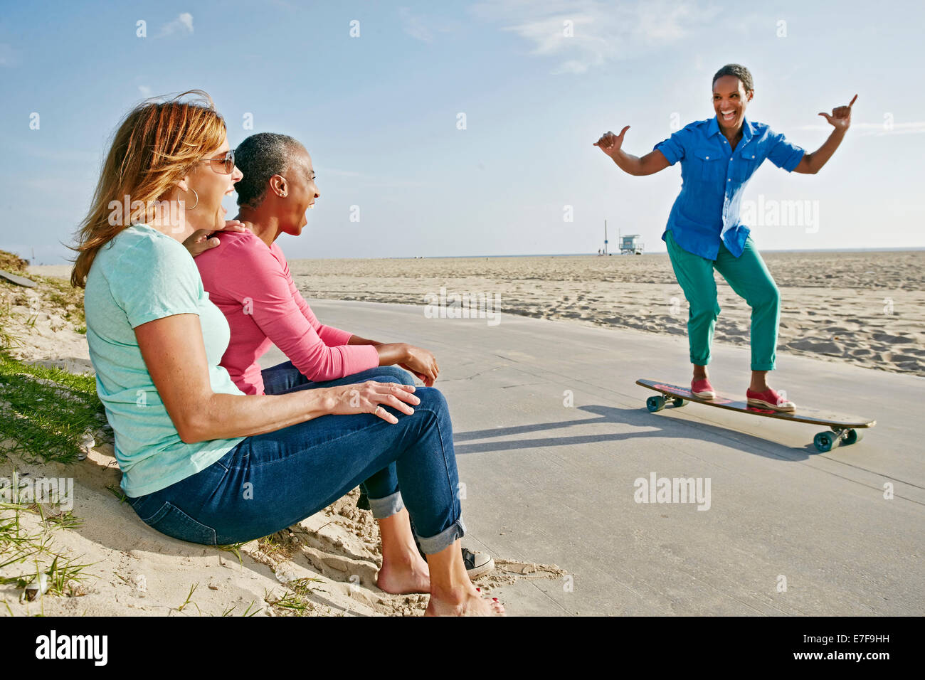 I vecchi Nero donna lo skateboard da amici sulla spiaggia Foto Stock