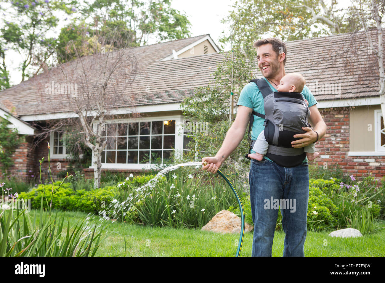 Padre caucasica holding baby e impianti di irrigazione Foto Stock