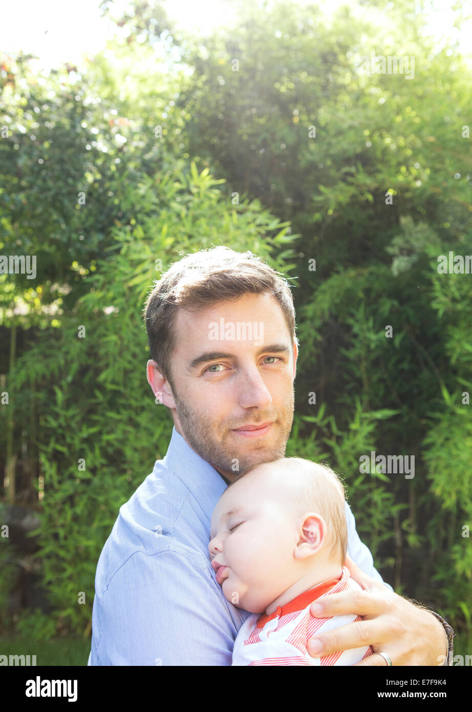 Padre caucasica holding baby in cortile Foto Stock