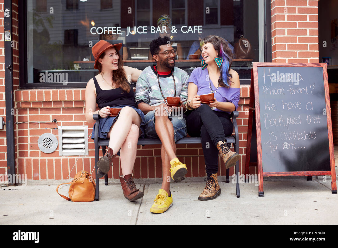 Gli amici seduti al di fuori di una caffetteria sulla strada di città Foto Stock