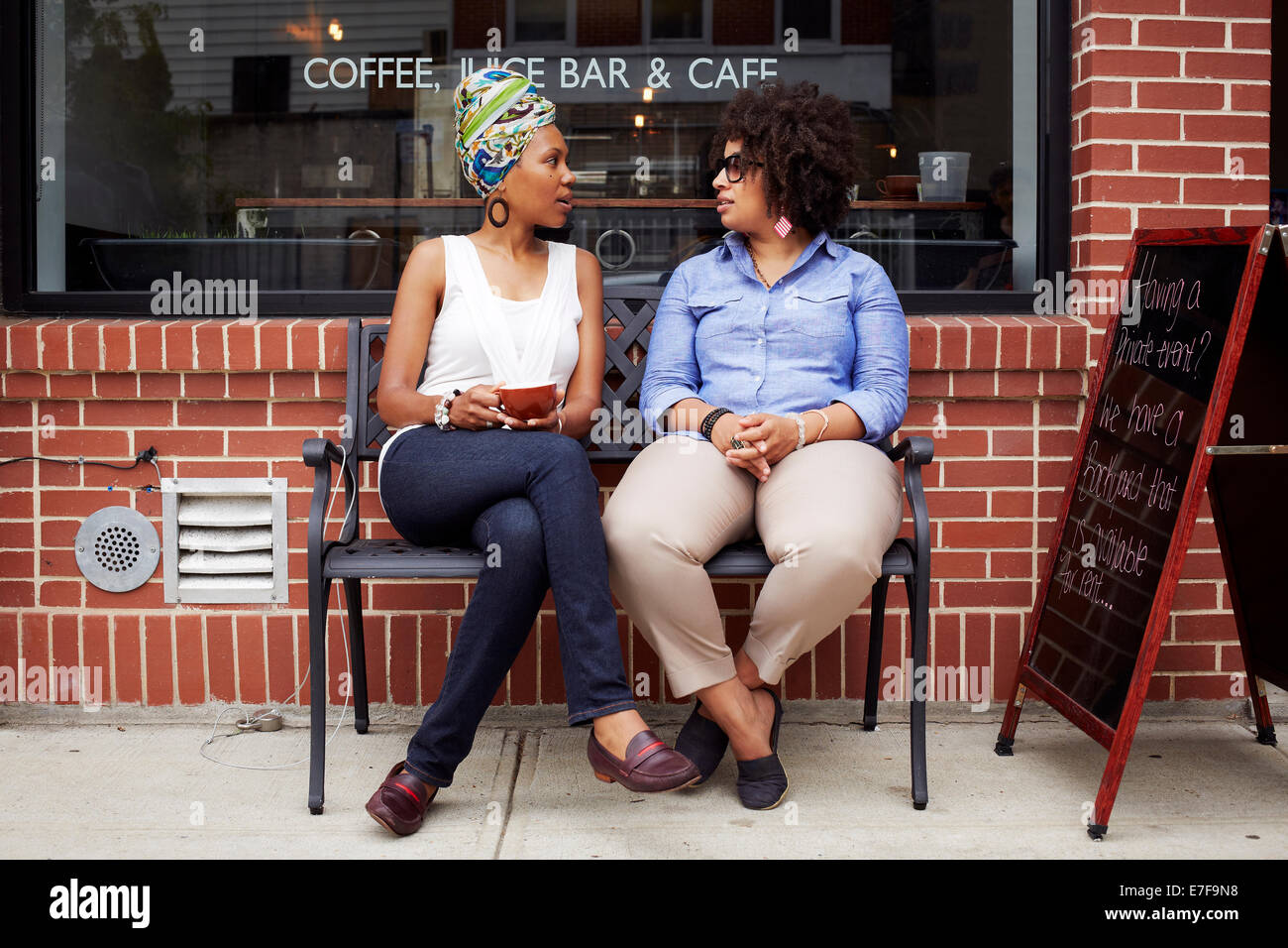 Le donne di parlare al di fuori di una caffetteria sulla strada di città Foto Stock