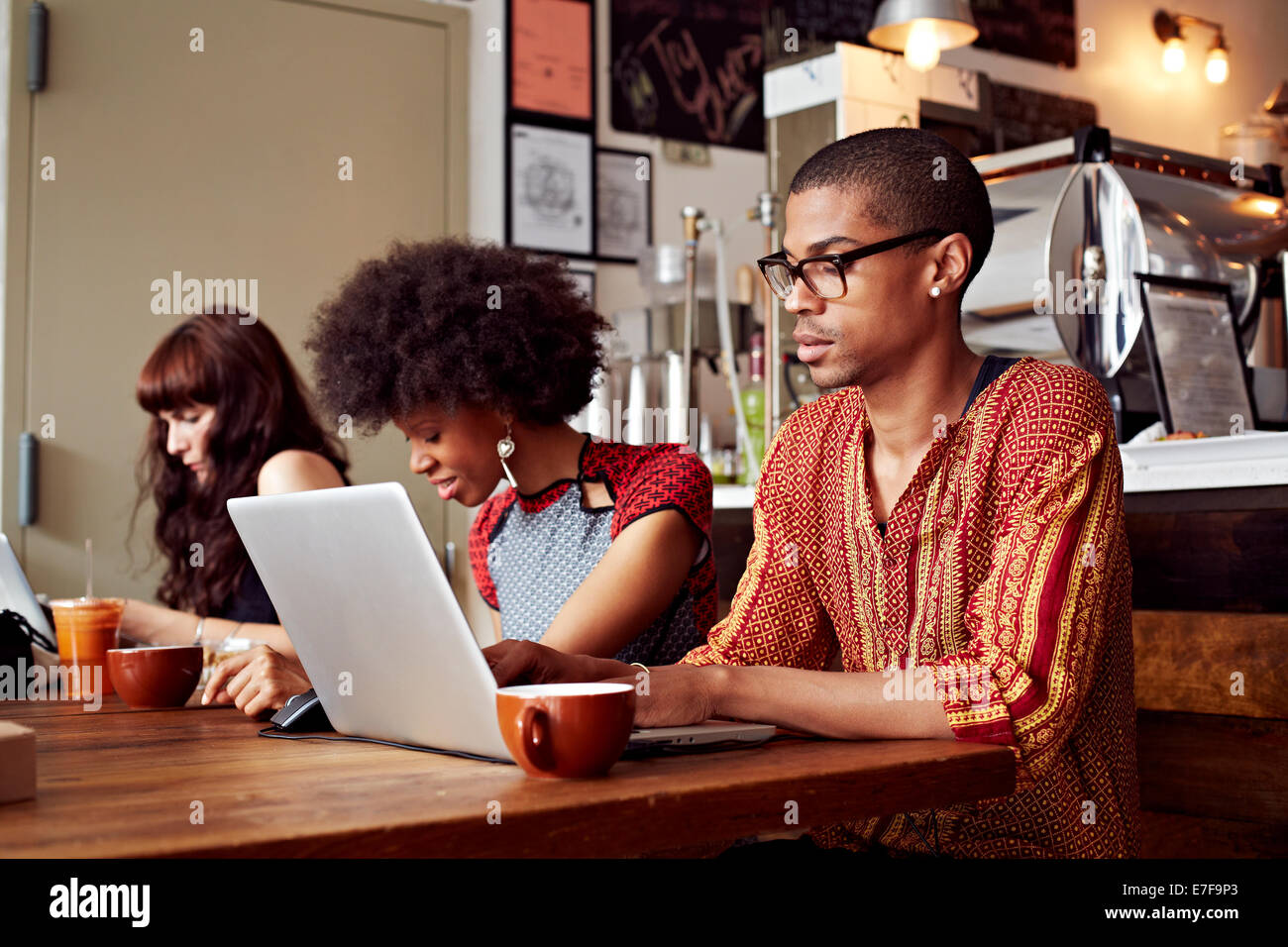 Le persone che usano la tecnologia in coffee shop Foto Stock