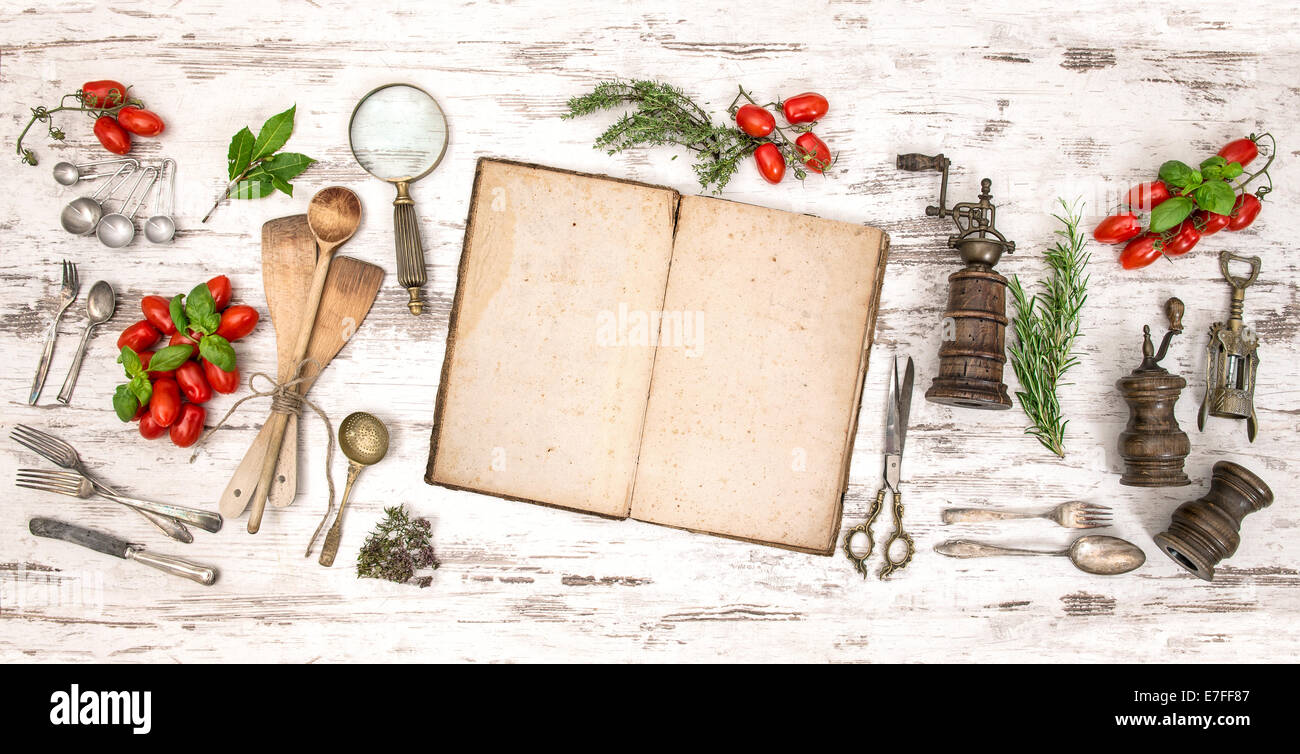 Il vecchio libro di cucina con verdure, erbe e vintage utensili da cucina. In stile retrò tonica foto Foto Stock