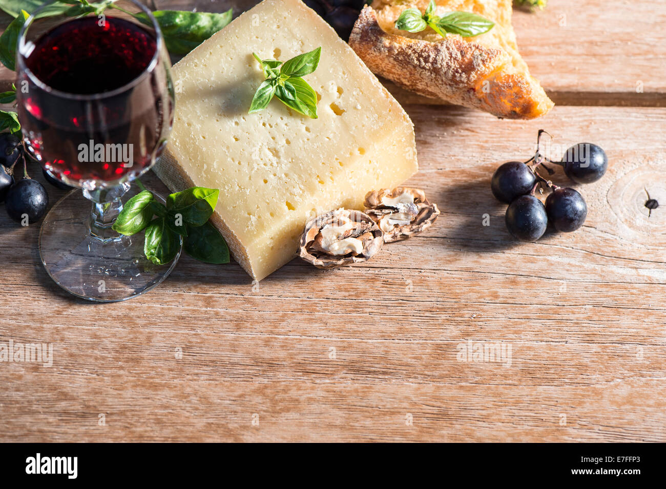 Formaggio con vino rosso, noci, foglie di basilico e uva. ingredienti alimentari. low key foto di stile Foto Stock