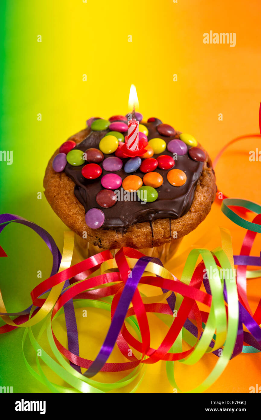 Tortina di compleanno con candela che brucia e decorazione multicolore Foto Stock