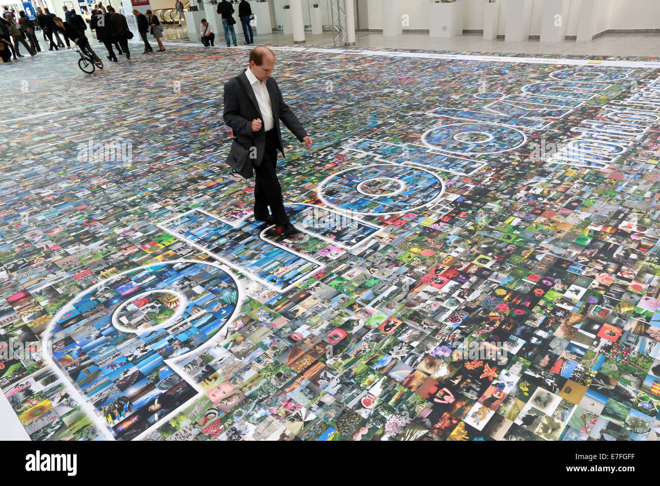 Persone che camminano su un pavimento coperto con migliaia di fotografie, Photokina 2014, Colonia, Germania Foto Stock