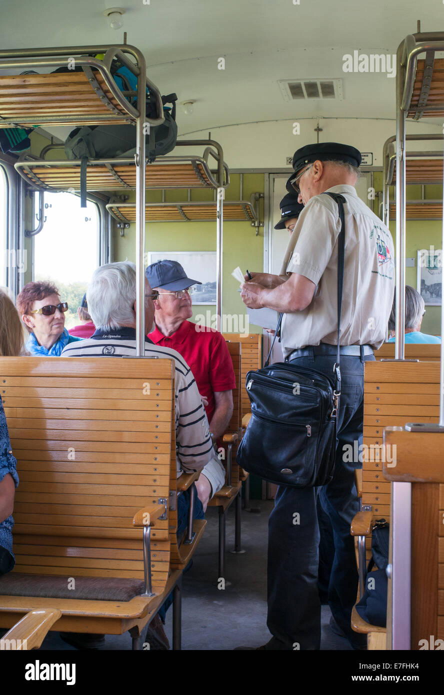 Conduttore sul Chemin de Fer de la Baie de Somme ispeziona i passeggeri' biglietti all'interno di un treno, in Francia, in Europa. Foto Stock