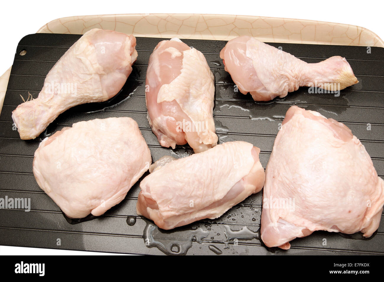Lo sbrinamento le cosce di pollo & cosce su un super vassoio di sbrinamento per accelerare il naturale processo quindi portarli a temperatura ambiente più rapidamente. Foto Stock