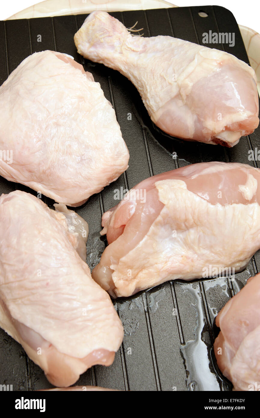 Lo sbrinamento le cosce di pollo & cosce su un super vassoio di sbrinamento per accelerare il naturale processo quindi portarli a temperatura ambiente più rapidamente. Foto Stock