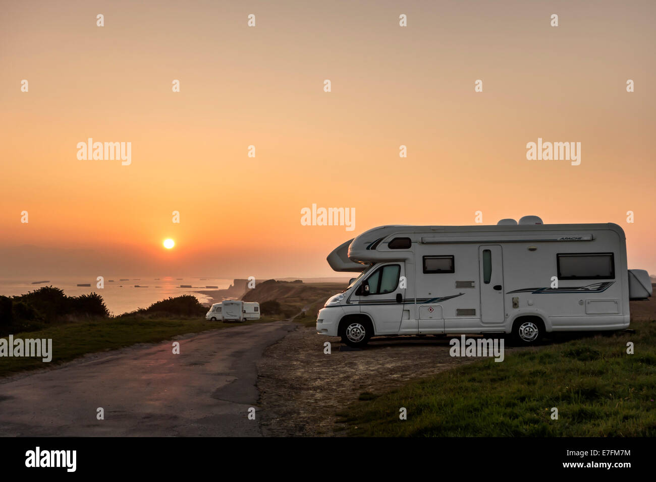I camper parcheggiato in un parcheggio per roulotte / veicolo per attività ricreative lungo la costa al tramonto con vista sul mare Foto Stock