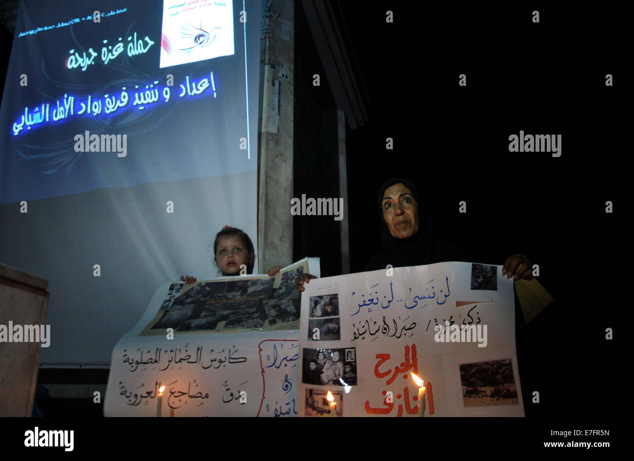 La città di Gaza, Striscia di Gaza, Territori palestinesi. 16 Sett 2014. Una donna Palestinese e della sua attesa duaghter cartelloni in una manifestazione di protesta per la marcatura del 48esimo anniversario dei massacri di Sabra e Shatila nel 1982, nella città di Gaza il 16 settembre 2014. I massacri di Sabra e Shatila è stata la macellazione di tra 762 e 3.500 civili, soprattutto palestinesi e sciiti libanesi, dal partito Kataeb, un libanese milizia cristiana, nel quartiere di Sabra e Shatila adiacenti campo profughi a Beirut, in Libano. Il 7 settembre 15, 63 palestinesi sono stati identificate individualmente e ucciso da un Israeliano unità denominata Sayeret Mat Foto Stock