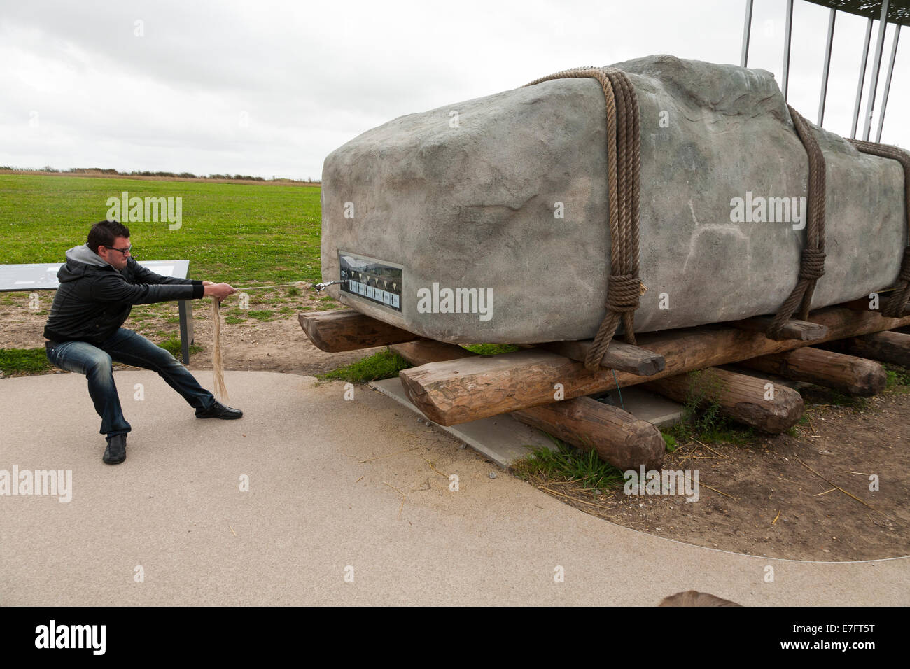 Visitatore / visitatori / turistico / turisti cerca / cerca di tirare una pietra di peso analogo a quelli che compongono il cerchio a Stonehenge. (70) Foto Stock