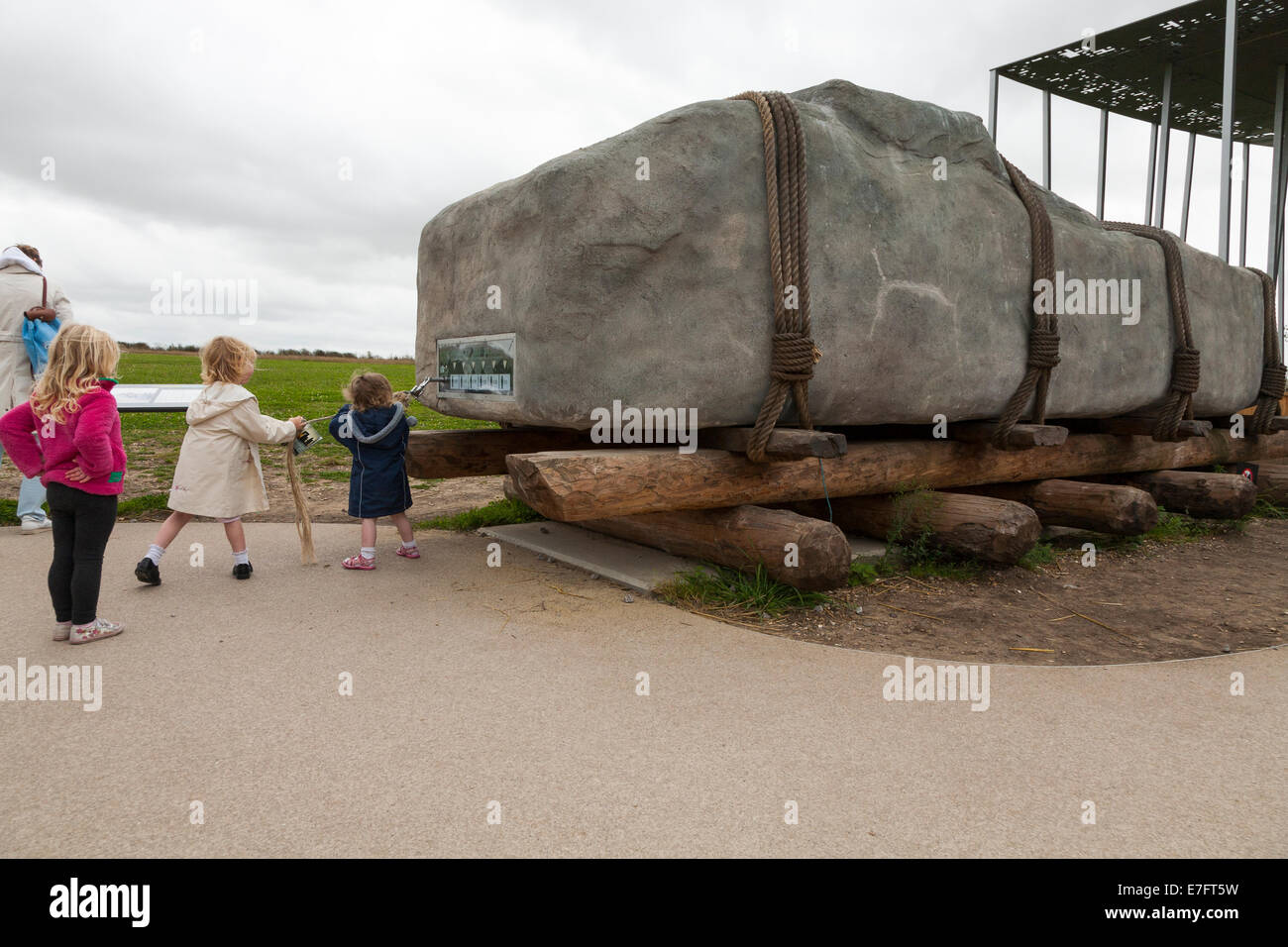 Visitatore / visitatori / turistico / turisti cerca / cerca di tirare una pietra di peso analogo a quelli che compongono il cerchio a Stonehenge. (70) Foto Stock