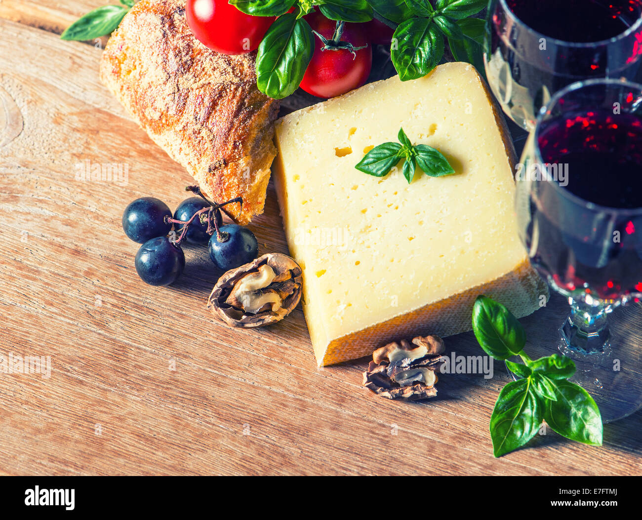 Formaggio con vino rosso e noci. Cibo e bevande in stile retrò tonica foto Foto Stock