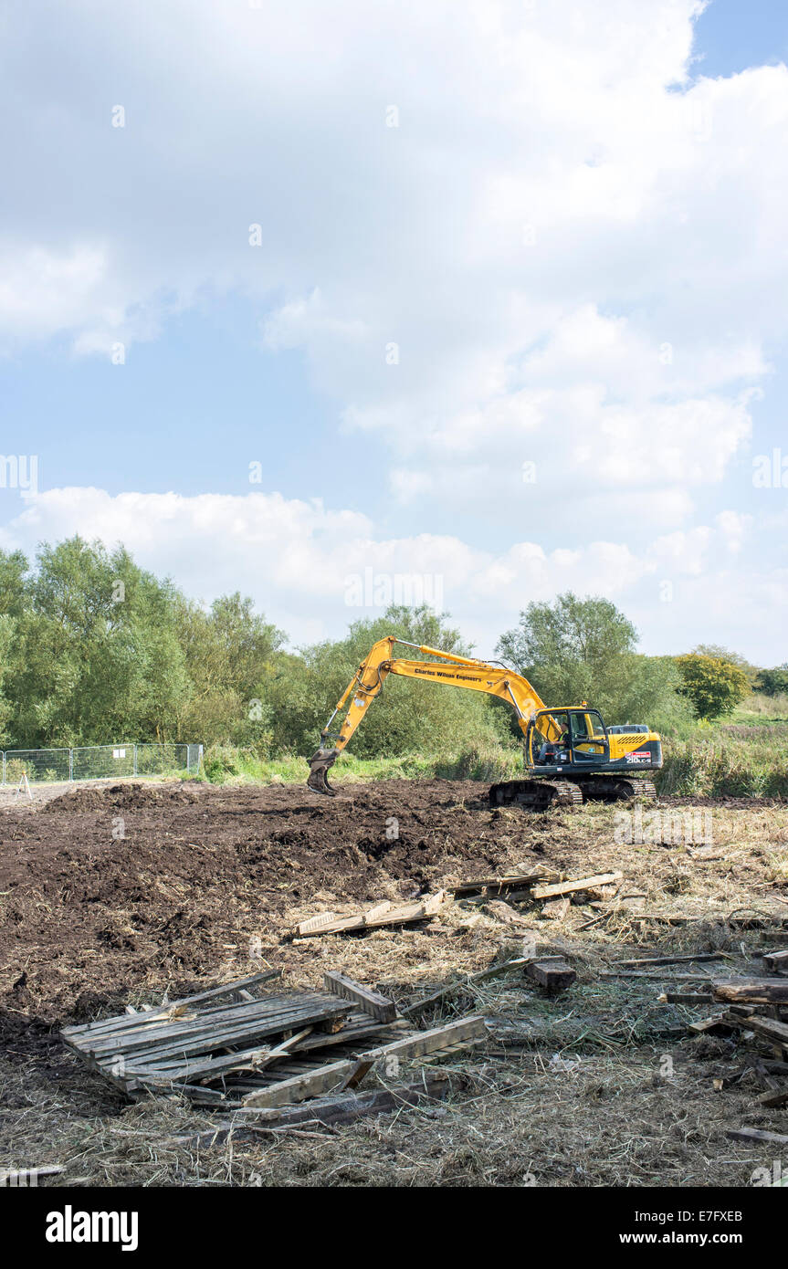 Grande macchina movimento terra lavorando sul letto reed progetto di restauro accanto al fiume Avon Salisbury Regno Unito Foto Stock