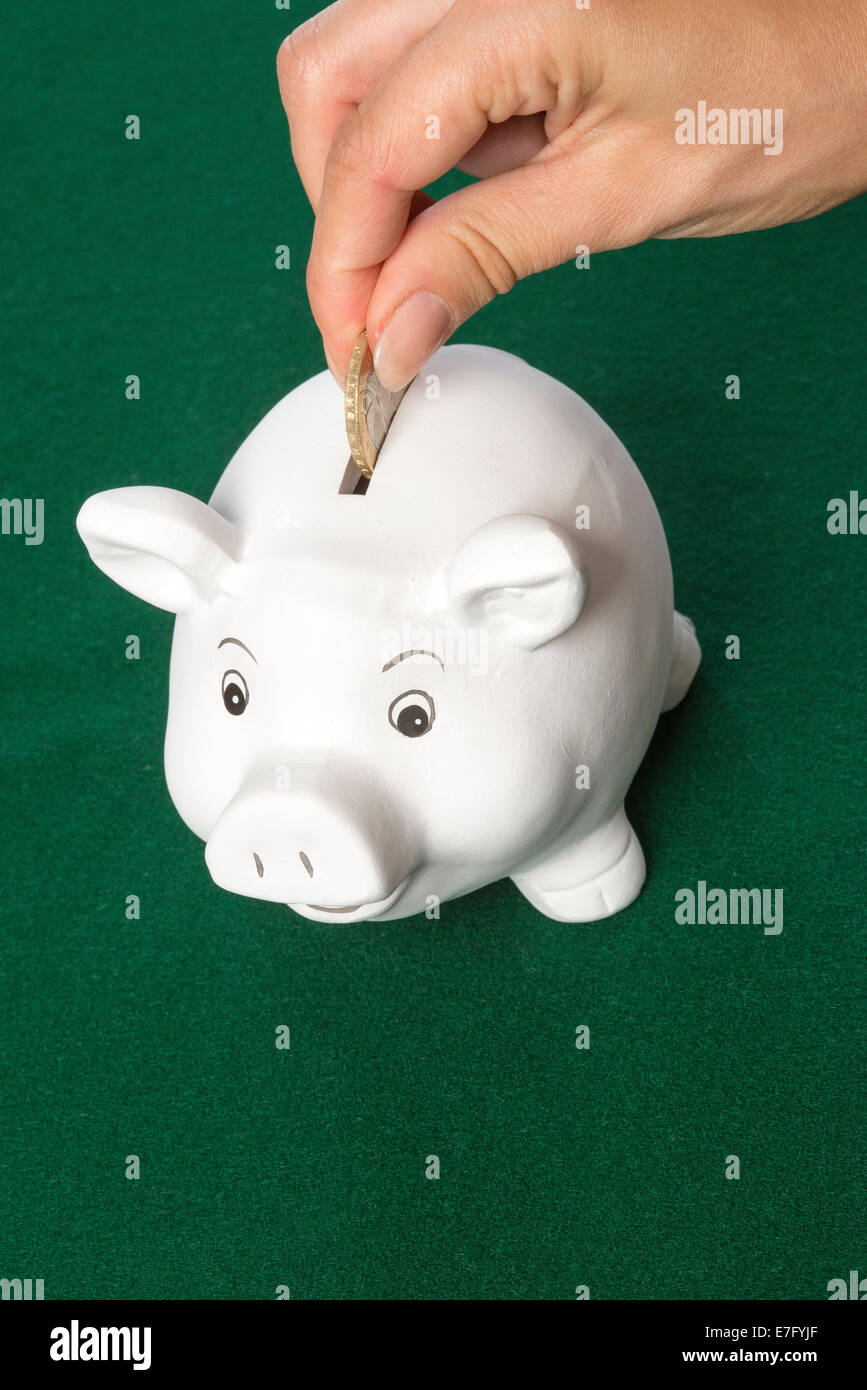 Salvadanaio di risparmio di denaro a due British pound coin andando nello slot Foto Stock