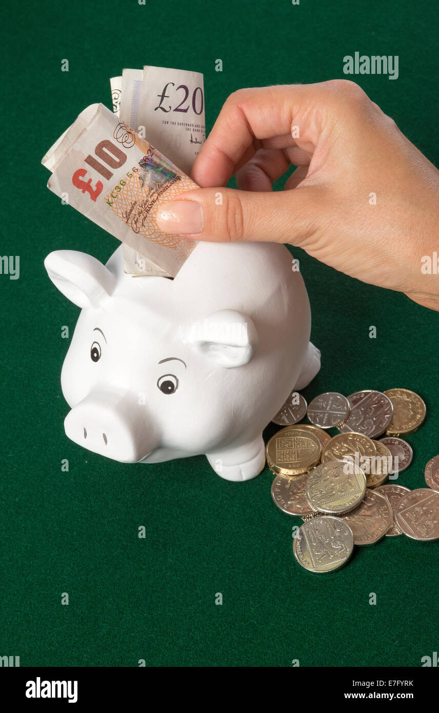 Salvadanaio con Sterling le banconote e le monete di donna risparmio di mano banconote britannico Foto Stock