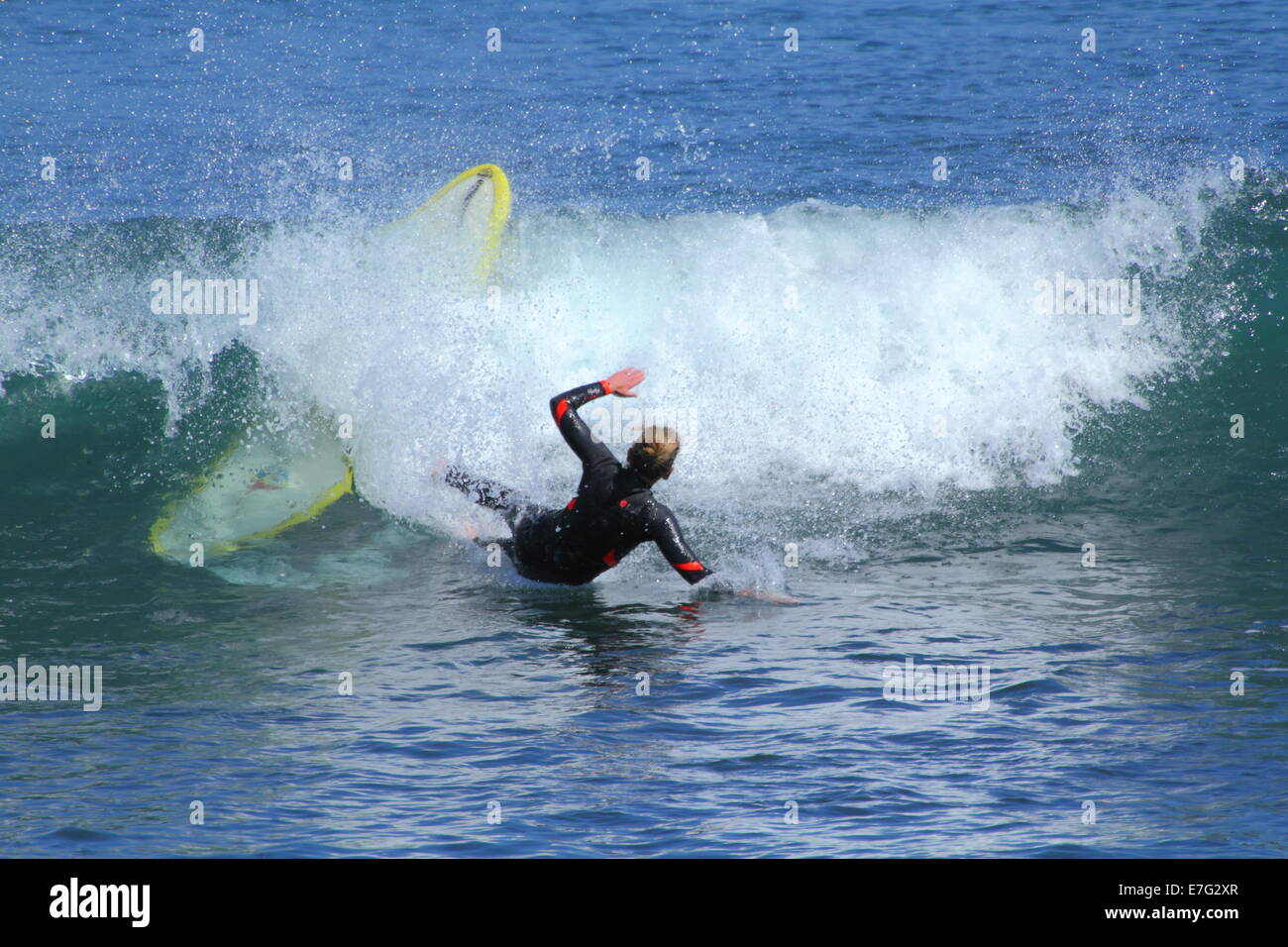 Una signora giovane surfer cade dalla sua tavola da surf in Oceano Indiano le onde a sud Cottesloe Beach, Cottesloe, Australia occidentale Foto Stock