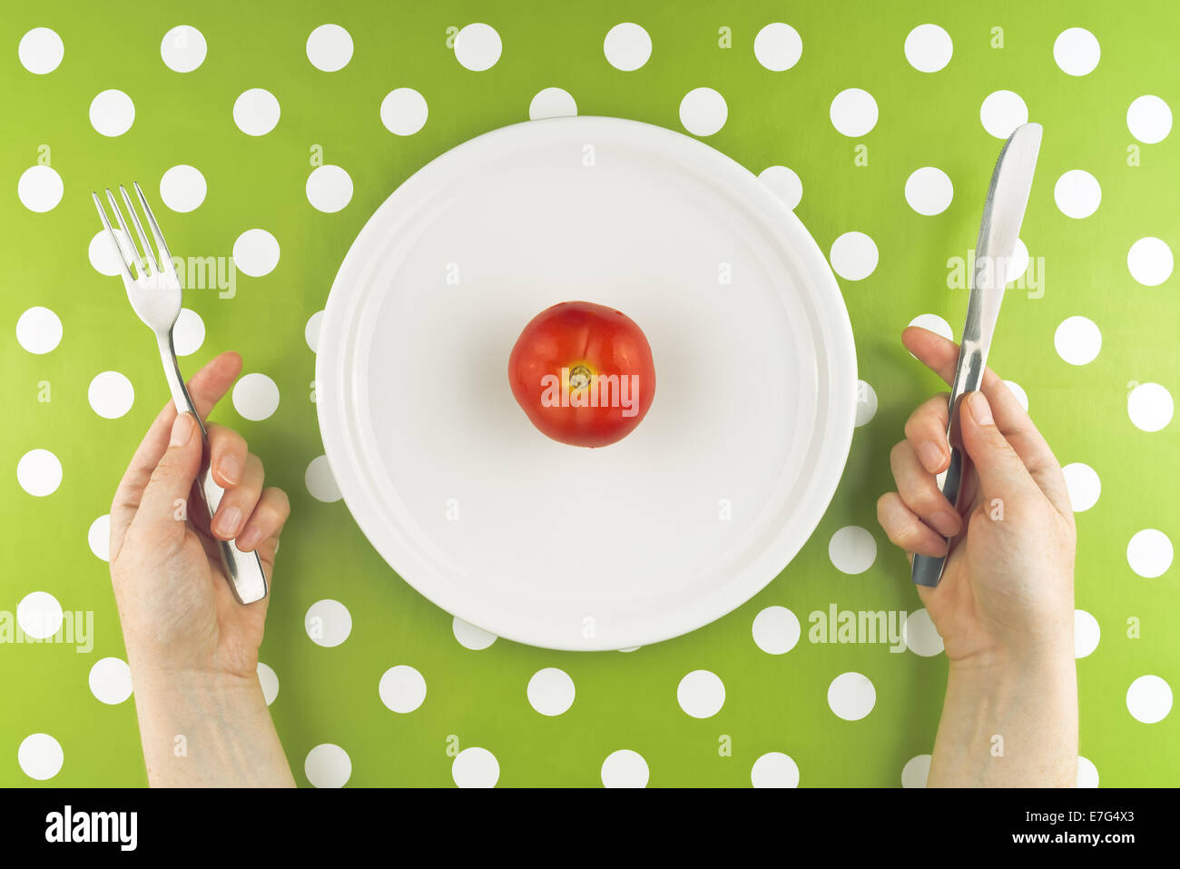 Donna di mangiare crudo fresco di pomodoro rosso su una piastra bianca, vista dall'alto. Foto Stock