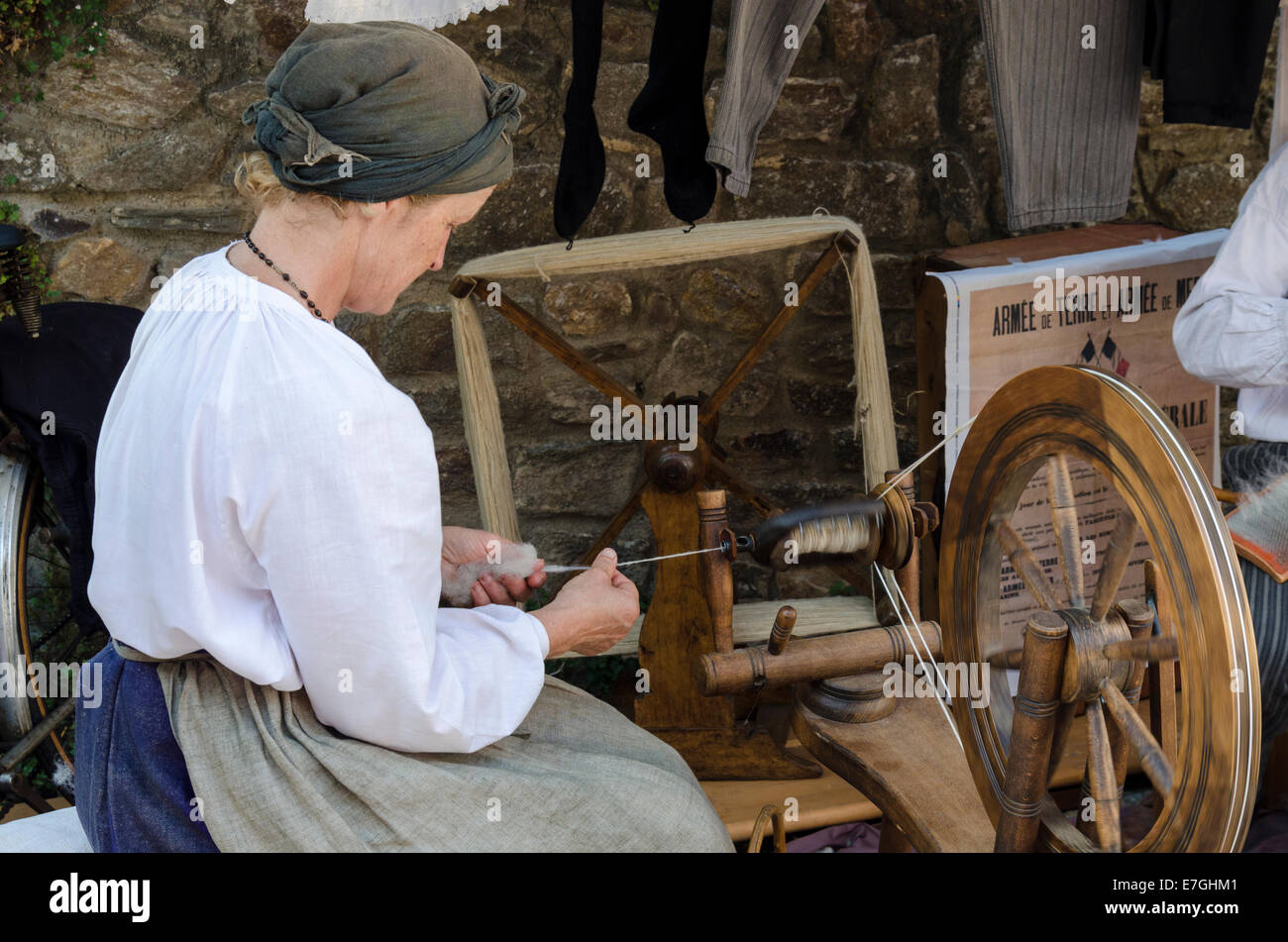 Dimostrazione di filatura della lana da una signora in tradizionale costume bretone Foto Stock