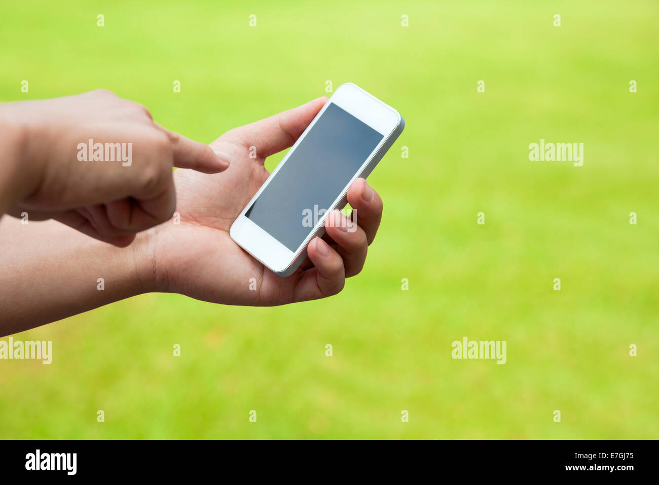 Touch screen mobile phone in mano con prato verde Foto Stock