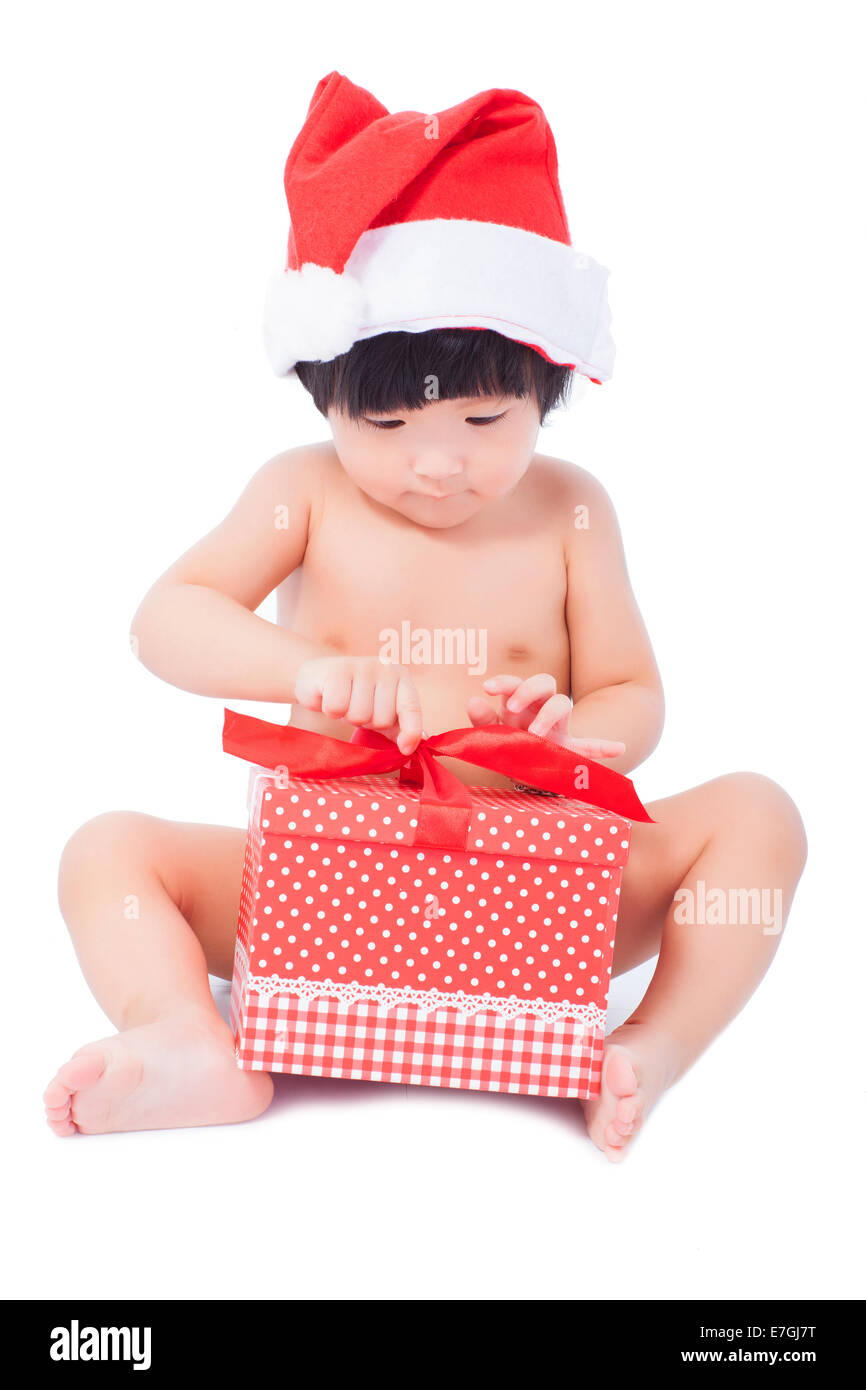 Curioso bambino in Santa cap guardando giftbox nelle sue mani Foto Stock