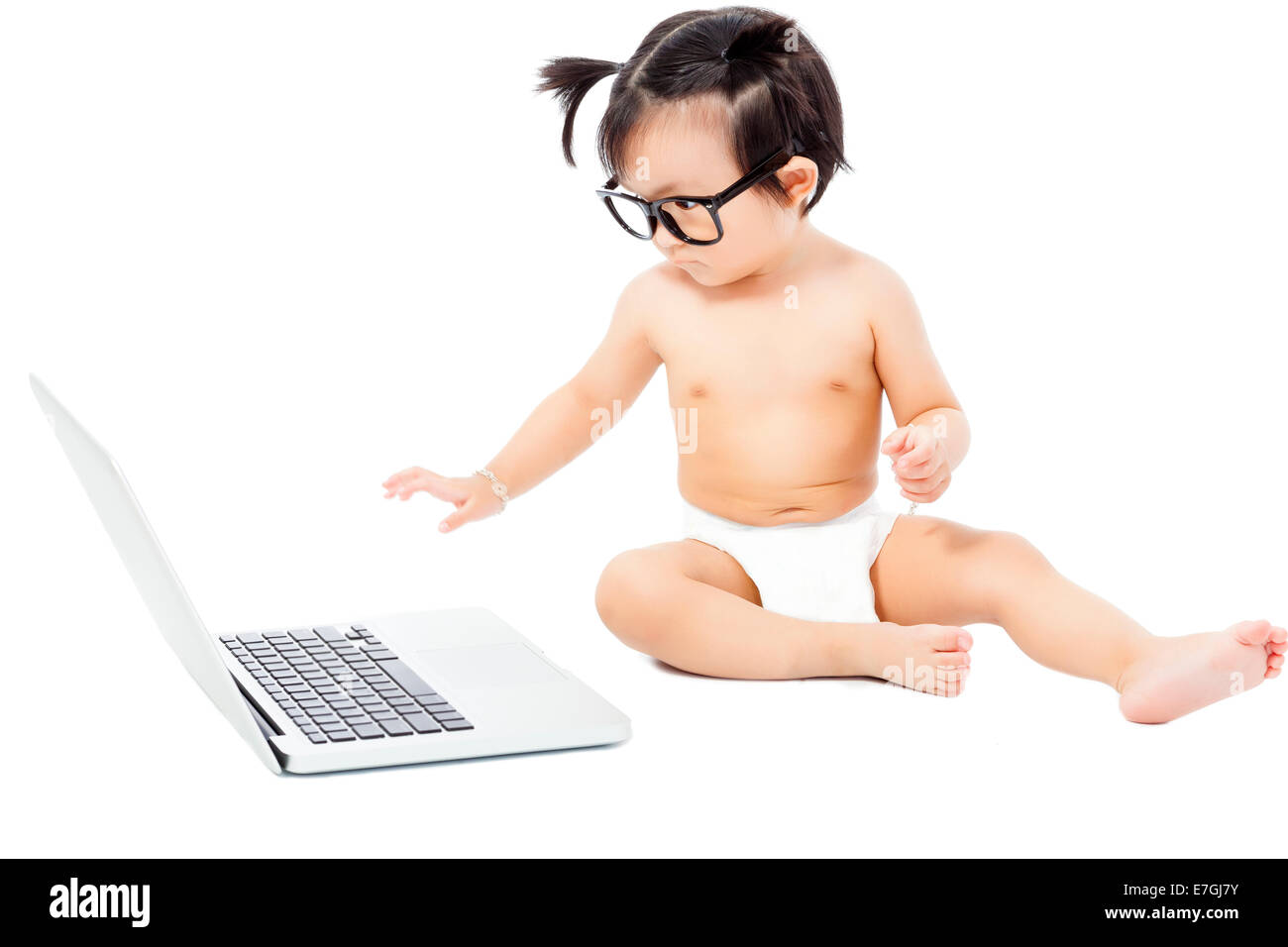 Piccolo bambino seduto a giocare su un laptop. isolato su sfondo bianco Foto Stock