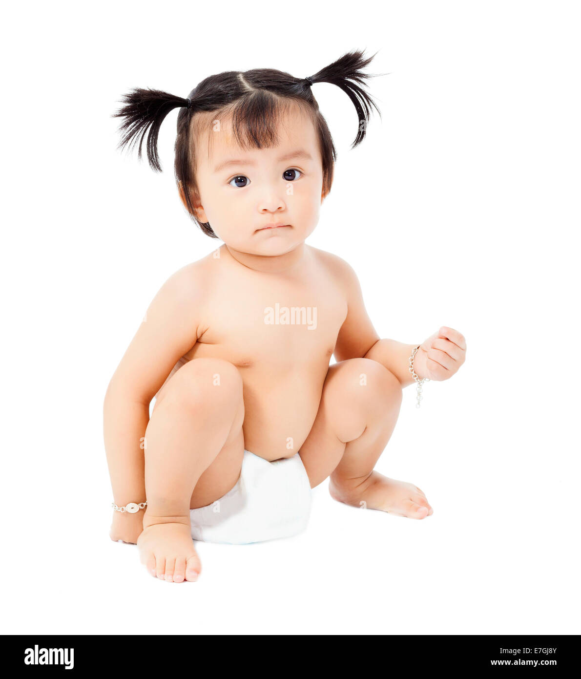 Carino Baby girl in un pannolino seduto e guarda in alto isolato su sfondo bianco Foto Stock