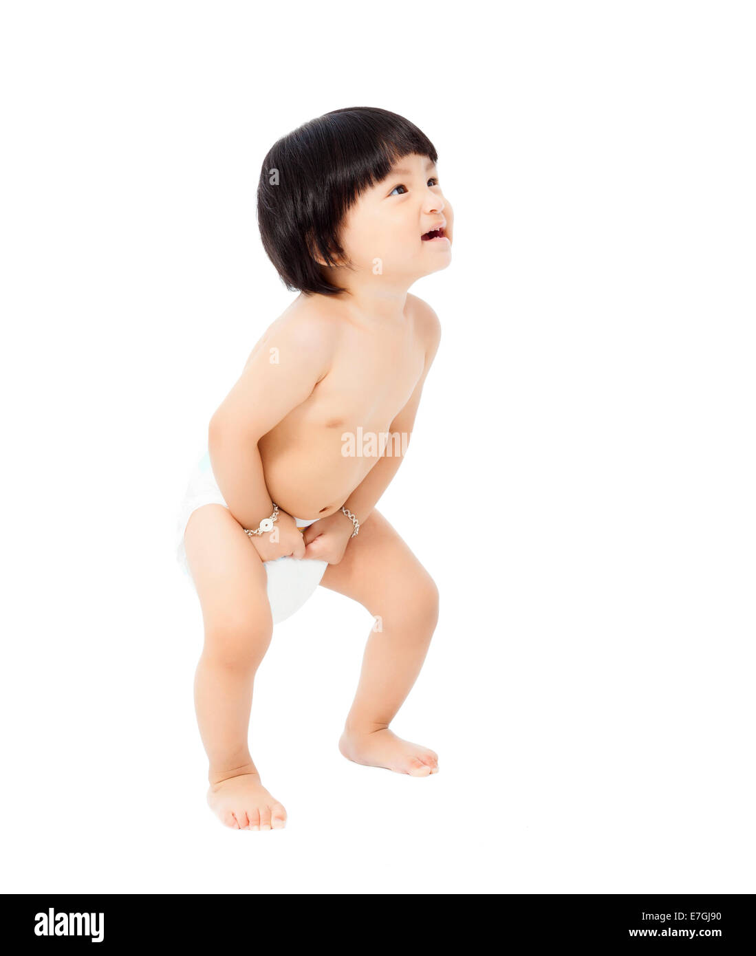 Happy Baby girl in un pannolino in piedi e guarda in alto isolato su sfondo bianco Foto Stock