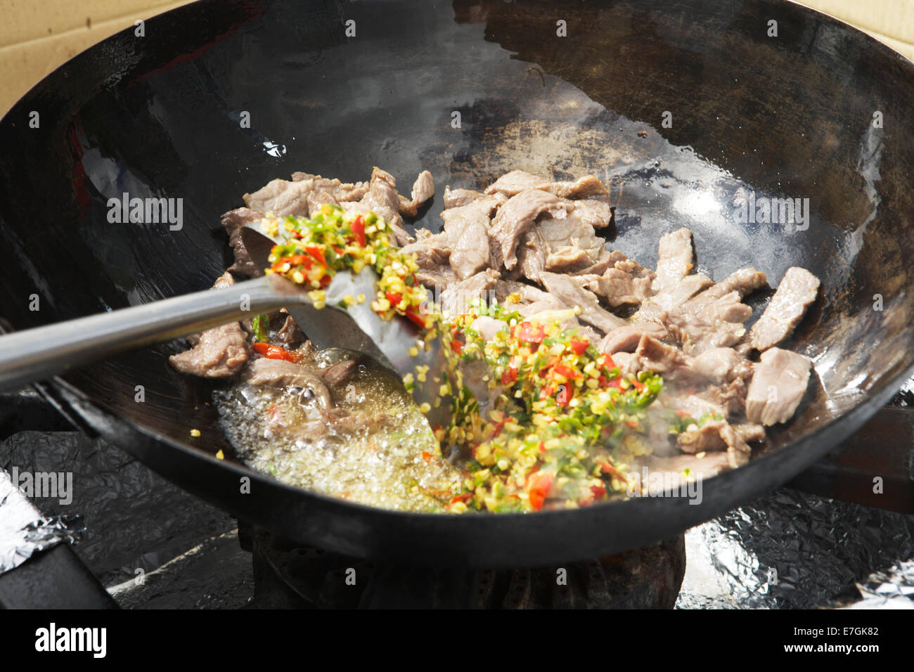 La cucina wok (rosolare la carne bovina, peperoncino, basilico): cibo asiatico, in un cibo di strada ora di pranzo mercato a Canary Wharf, London, Regno Unito Foto Stock