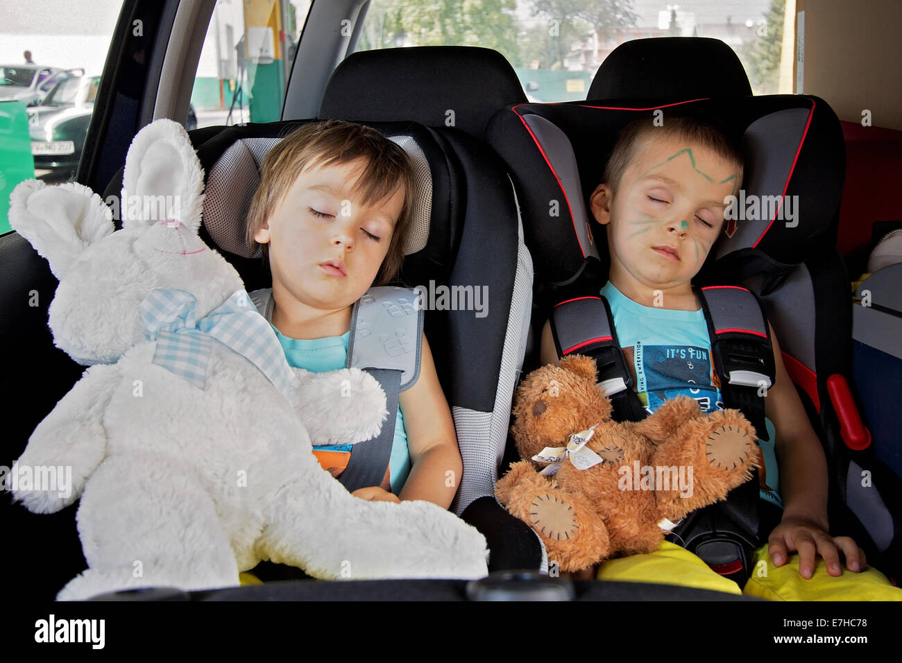 Due ragazzi in sedili per auto, viaggiare dormendo in auto con orsetti di  peluche Foto stock - Alamy