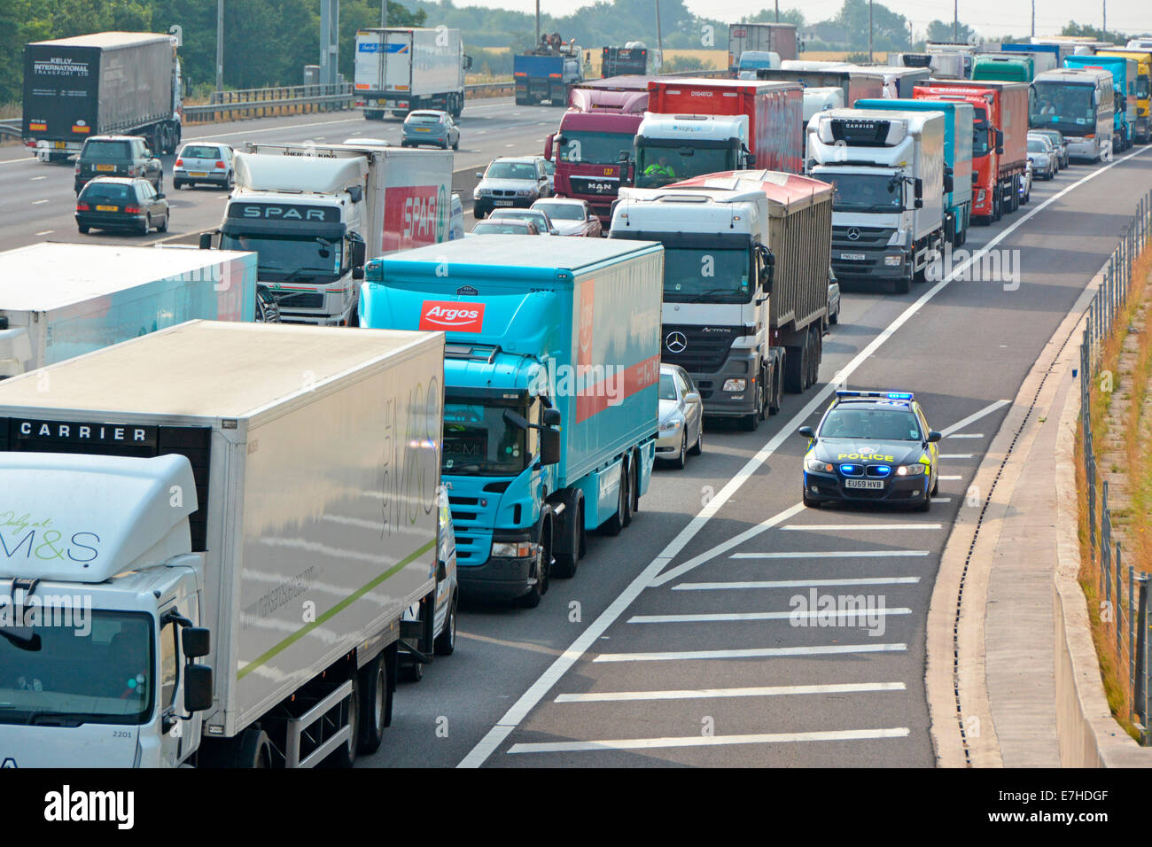 Essex Police BMW auto utilizzando la spalla dura per raggiungere la posizione di incidente di fronte a griglia Regno Unito autostrada camion & traffico auto Foto Stock