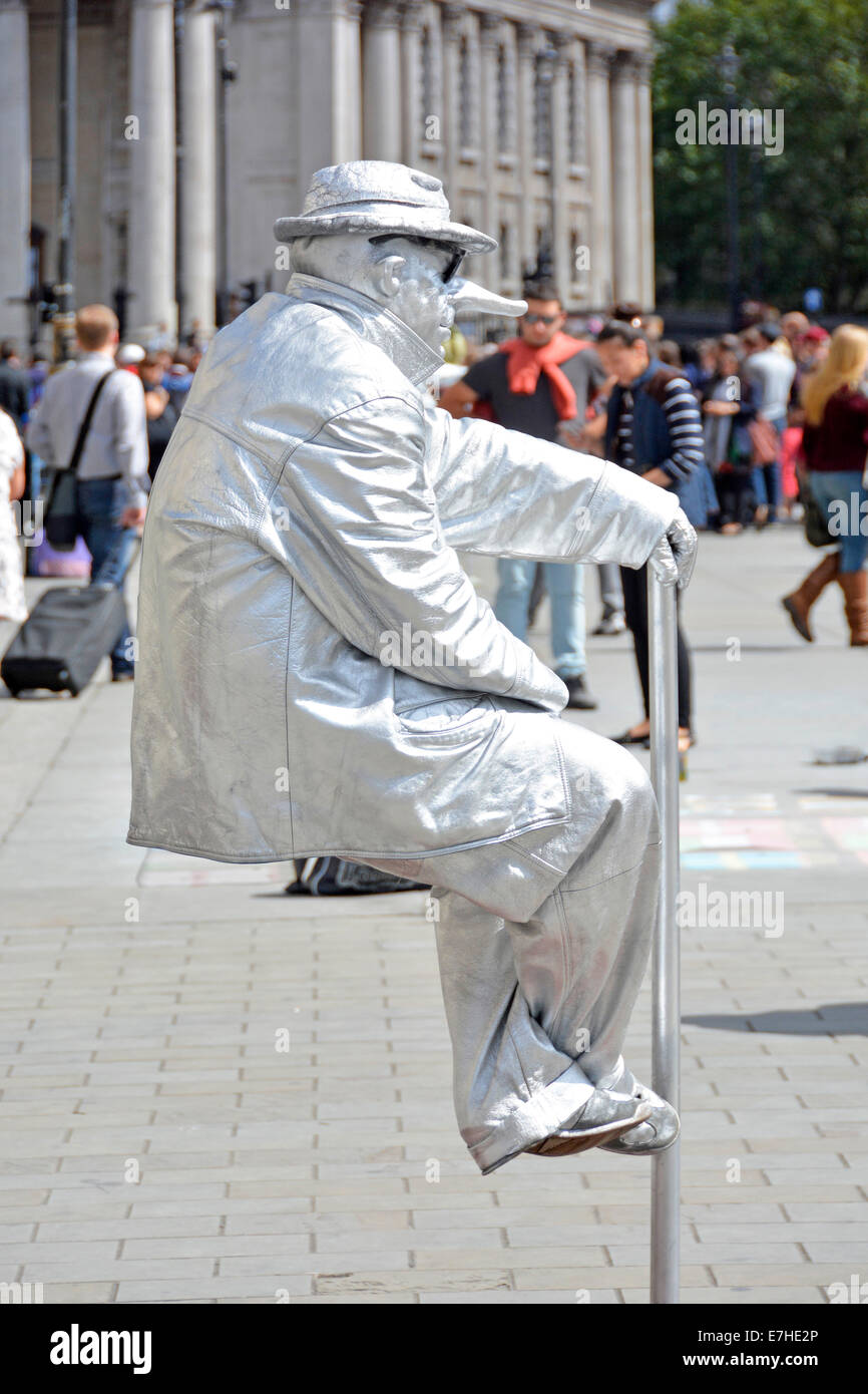 Persona vivente dell'artista di strada che siede ancora come statua nel trucco & costume apparentemente supporto invisibile o illusione ottica in Trafalgar Square Londra UK Foto Stock